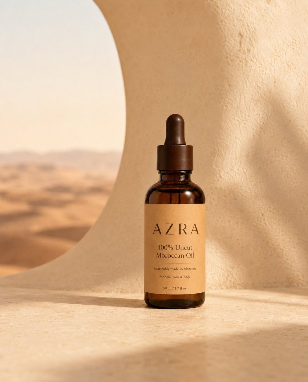 AZRA amber glass dropper bottle framed by a curved opening onto Moroccan desert dunes