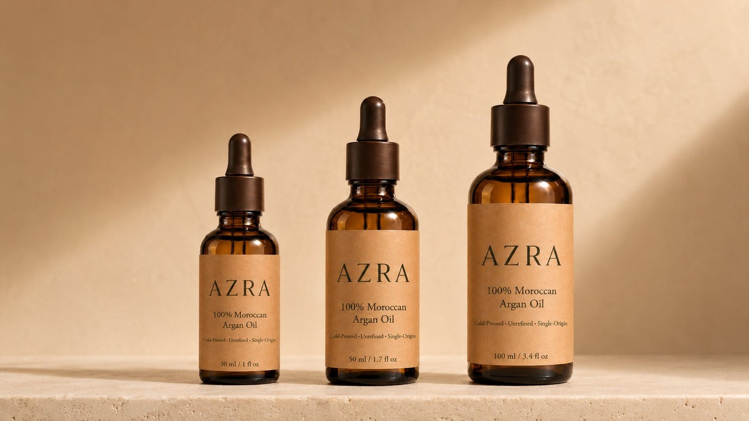 AZRA argan oil in three sizes — 30 ml, 50 ml and 100 ml — on a warm stone ledge